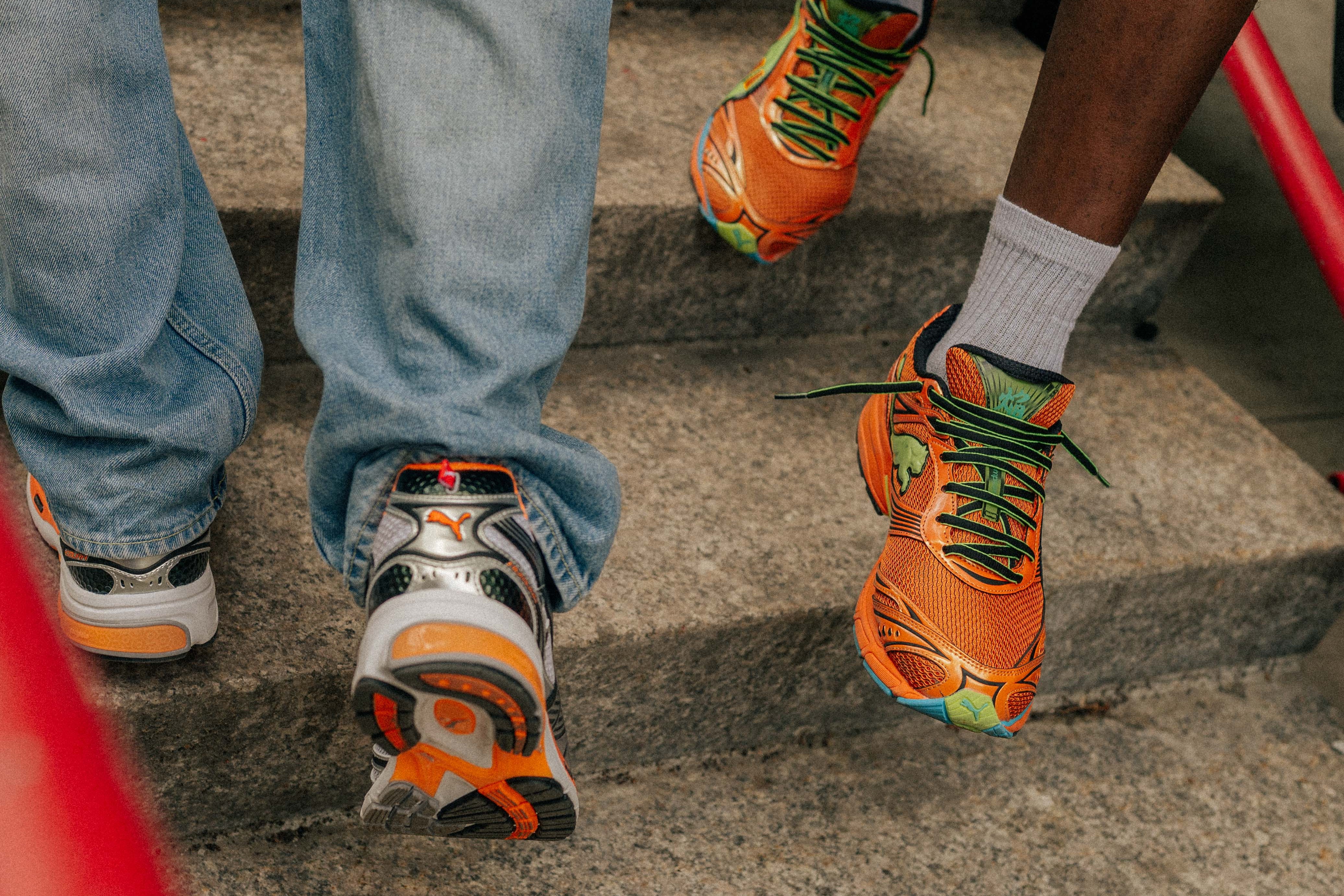 Two pairs of feet wearing colorful sneakers on a set of stairs.