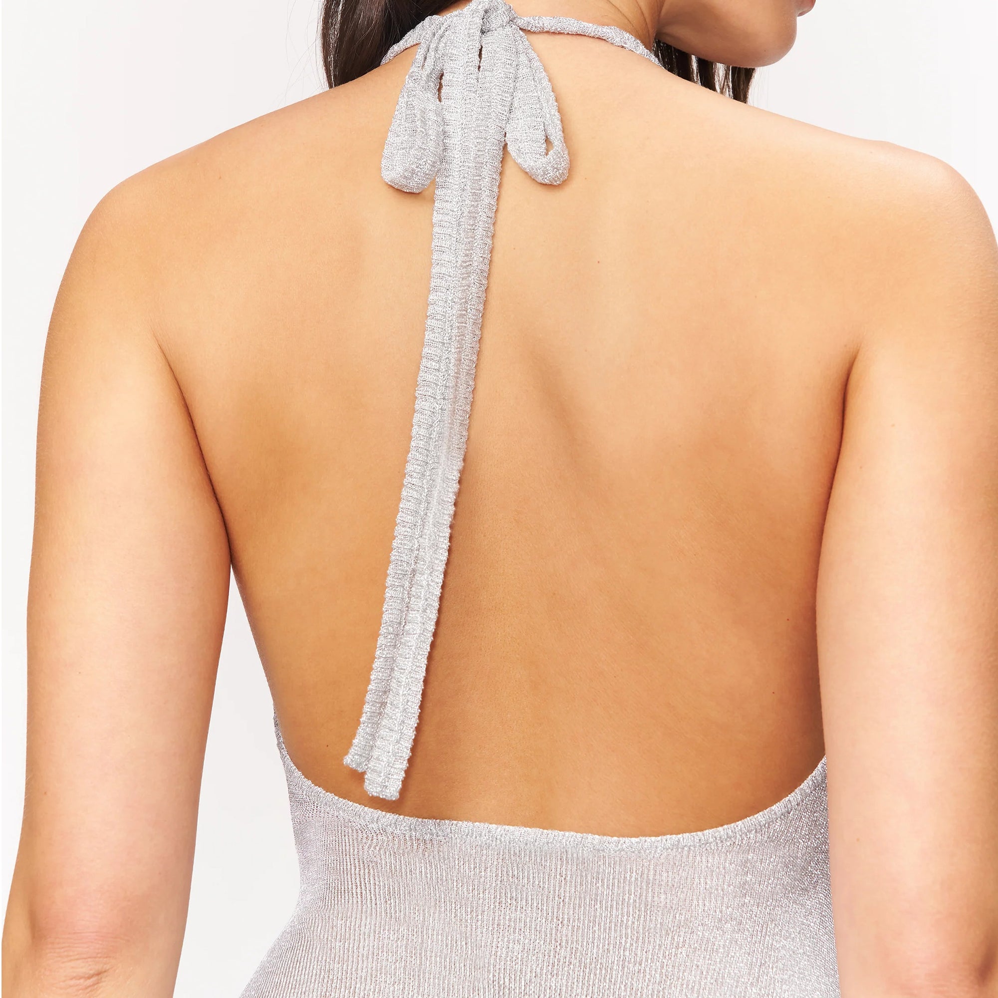 person wearing a silver halter mini dress on a white background