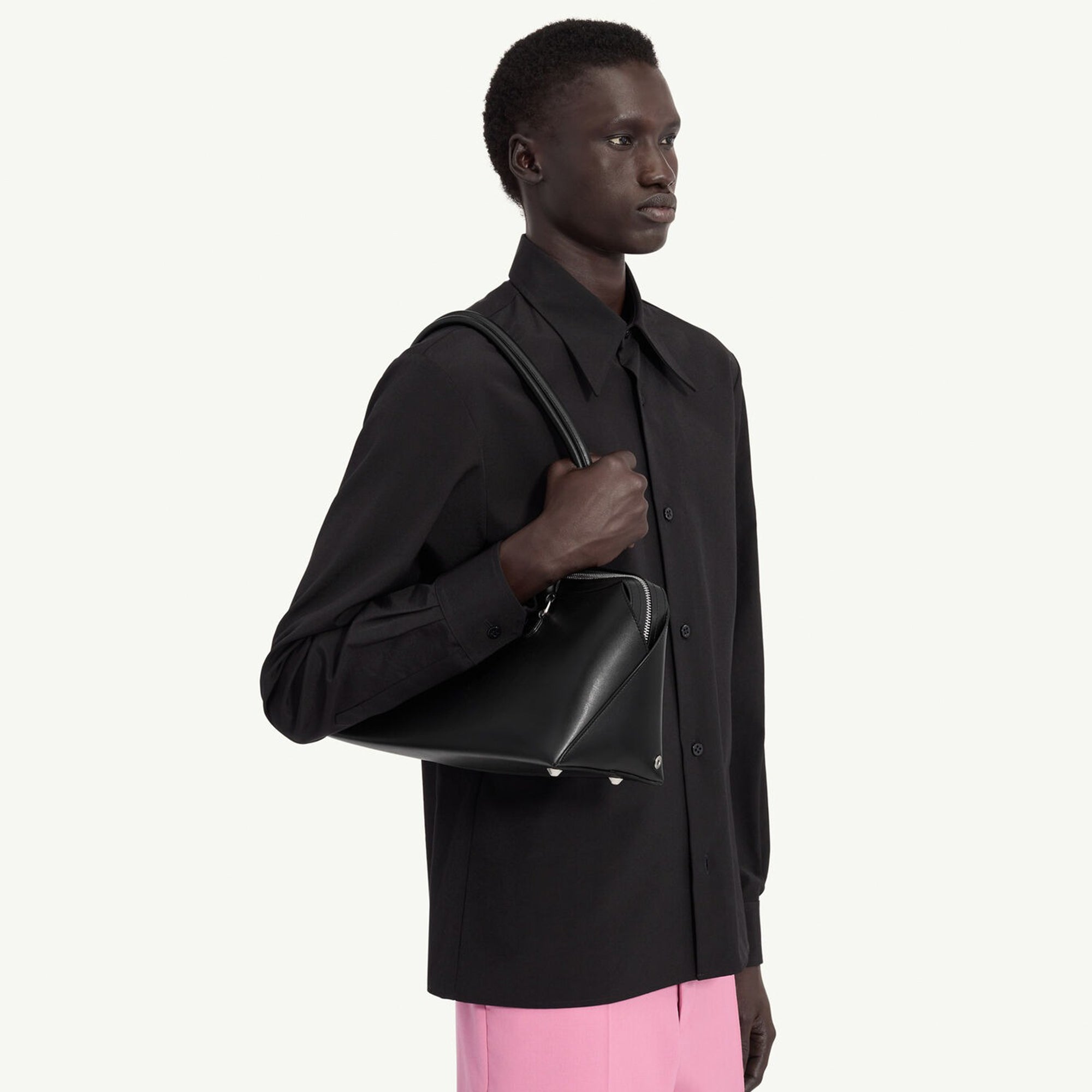 person holding black leather bag on a white background